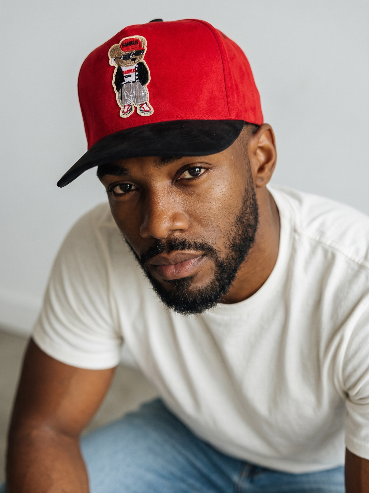 B-Is-TheBrand red and black baseball cap with an embroidered bear patch worn by a man in a white t-shirt