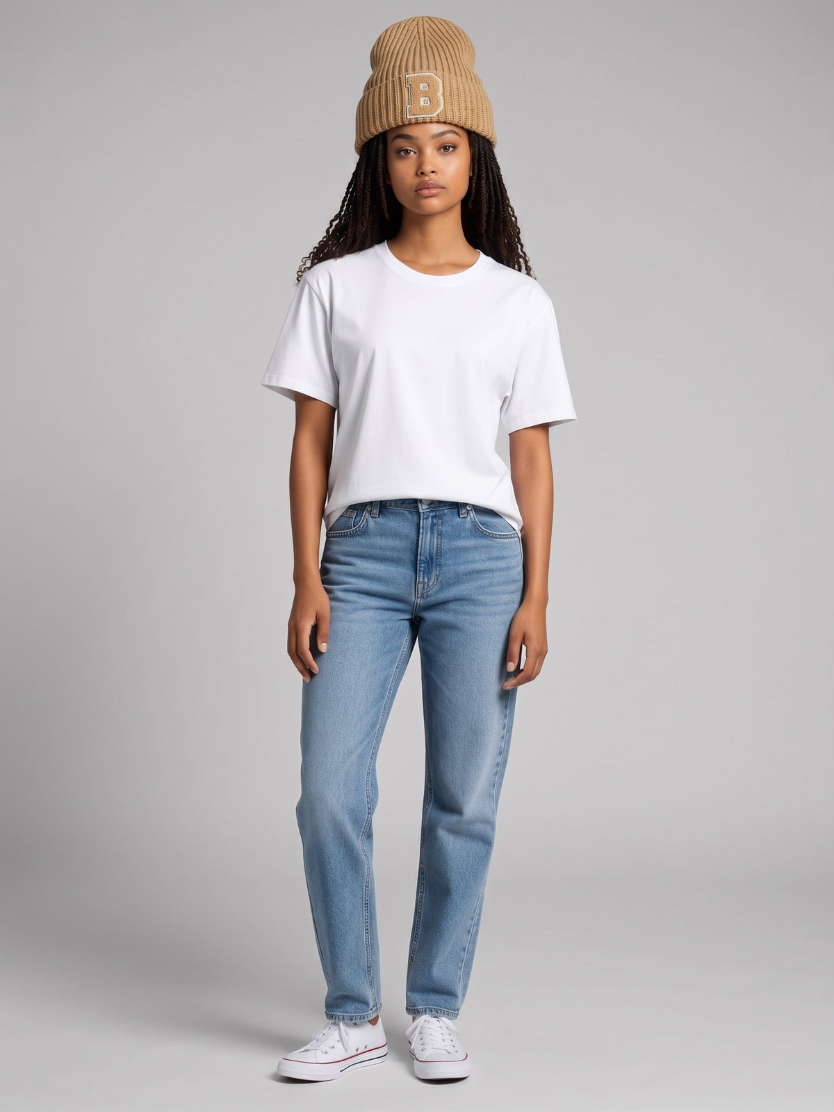 Model wearing a B-Is-TheBrand sand brown ribbed knit beanie with a B patch, white t-shirt, and blue jeans.